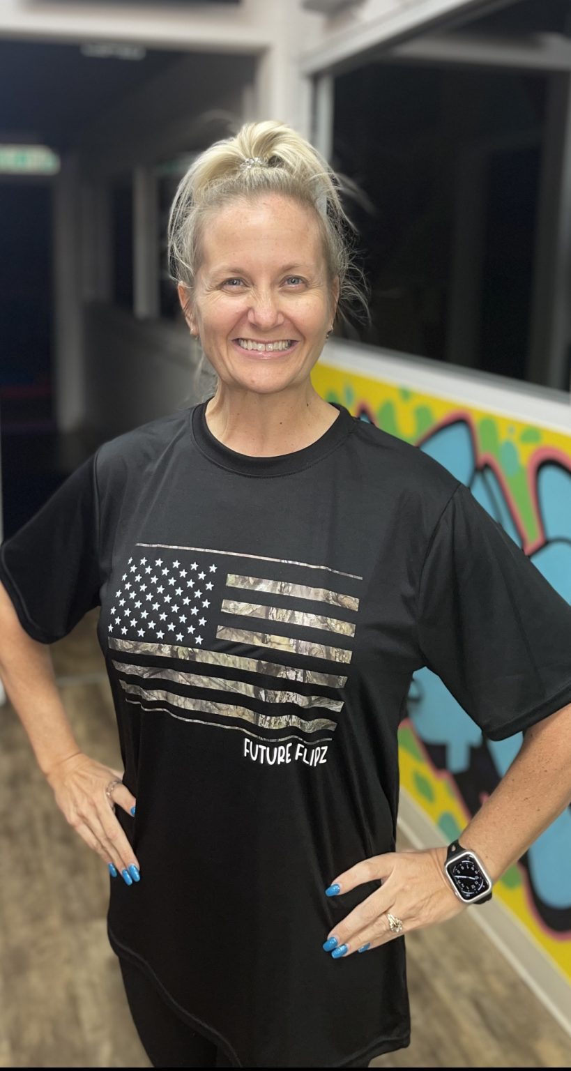 A smiling woman wearing a black American flag t-shirt.